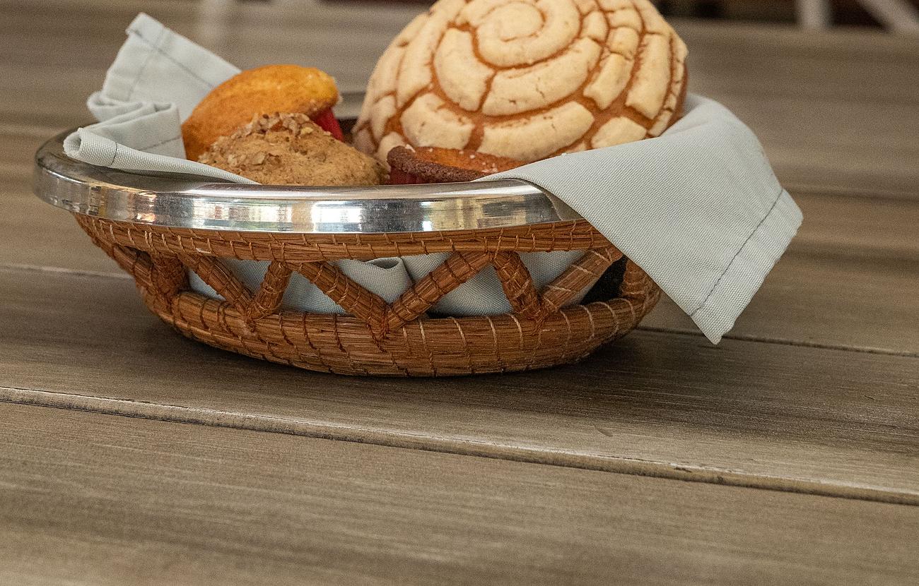 Fotograf&iacute;a de banco con licencia: una canasta de mimbre con una concha y otros panes sobre una mesa de madera.